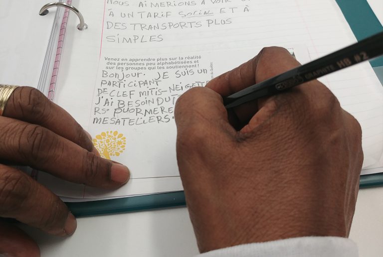 photo d'un main tenant un crayon et qui écrit sur une feuille de papier
